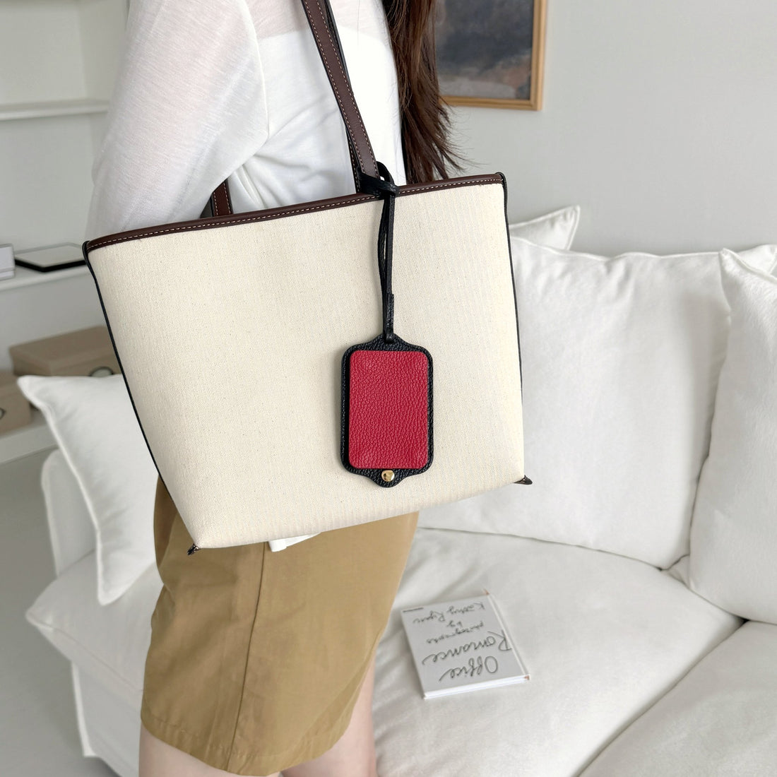 Aurekto leather photocard holder in Noir Rouge attached to an ivory tote bag as a bag charm